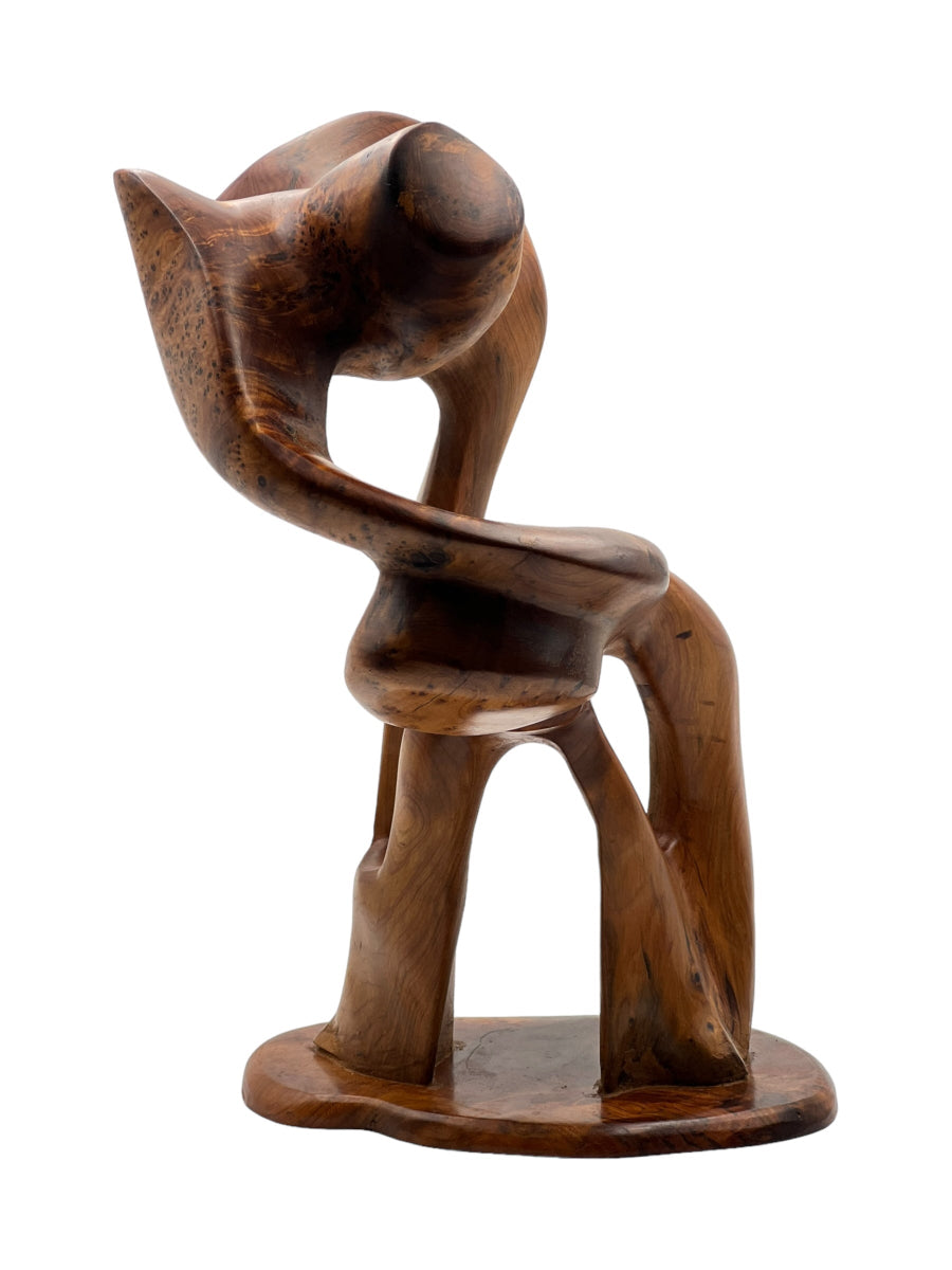 A wooden sculpture of a standing figure with its arms raised and slightly bent, with a smooth finish and a natural wood grain texture.