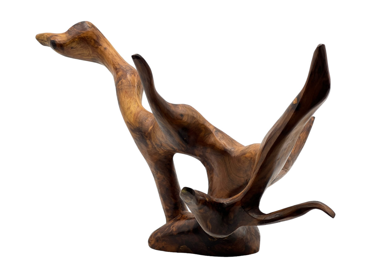 A brown wooden sculpture of an animal, possibly a bird or a dragon, with intricate details and a textured surface.