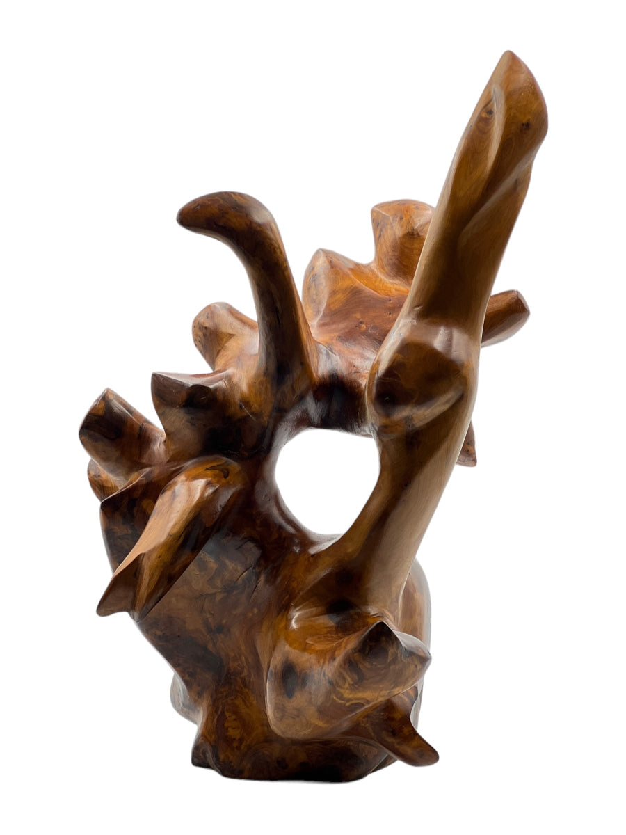 A brown wooden sculpture with a textured surface, depicting an abstract or figurative shape, part of the 3ar3ar Collection.