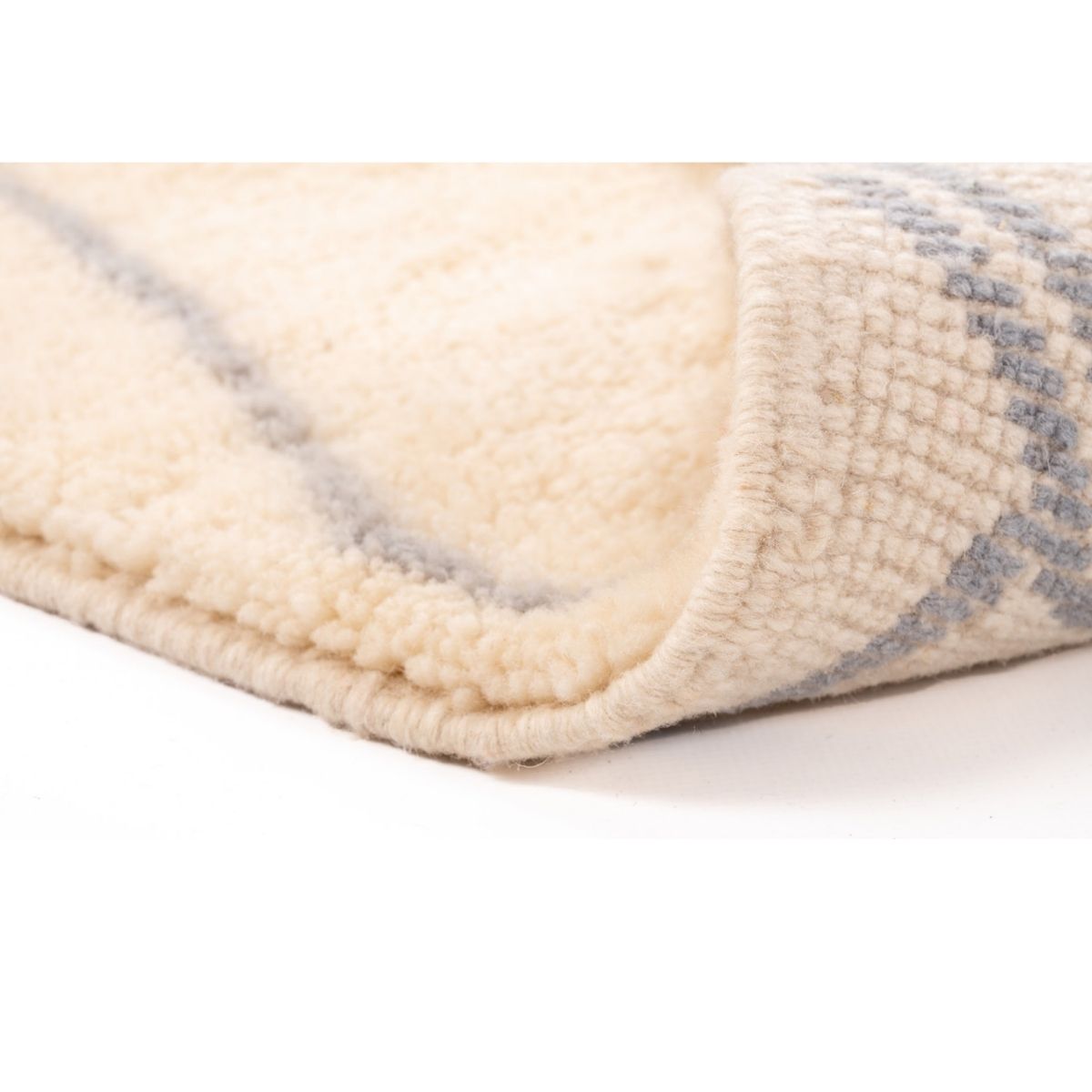 Close-up of a textured rug corner with a neutral color palette