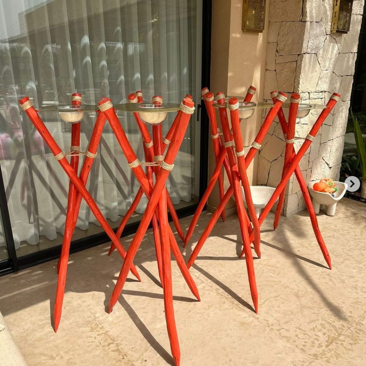 Red wooden stands with metal cylinder tops and glass bowls arranged outside a building.