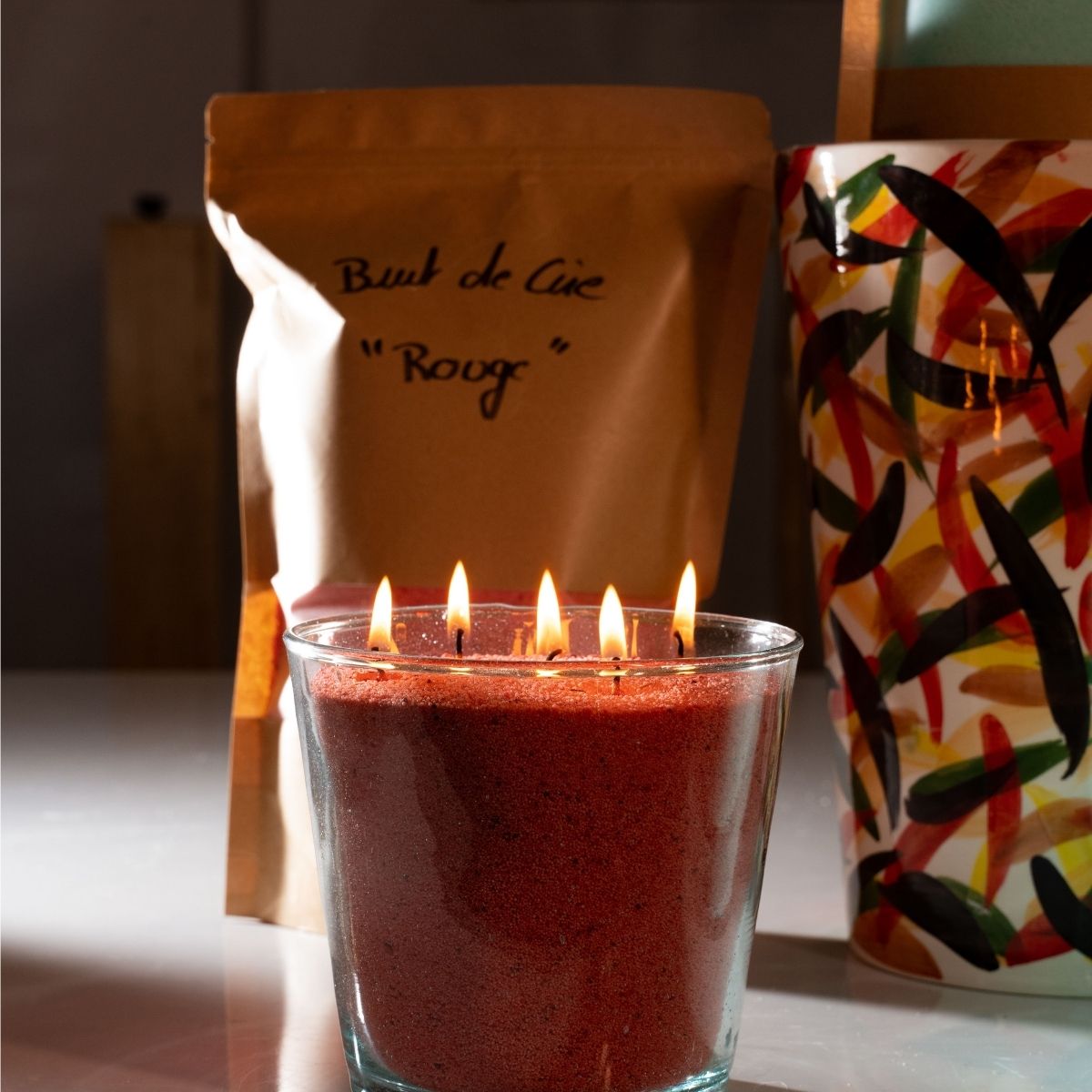 gnite elegance with this radiant red sand wax candle from Dary Living, designed to complement every mood and occasion. Crafted from our signature colored sand wax, it features five luminous flames gracefully burning within a handcrafted glass vessel, creating a captivating visual centerpiece.

The instant it’s lit, warmth envelops the room, transforming the ambiance into one of refined serenity. Perfect for romantic evenings, mindful self-care rituals, or enhancing sophisticated décor, this candle sets the 