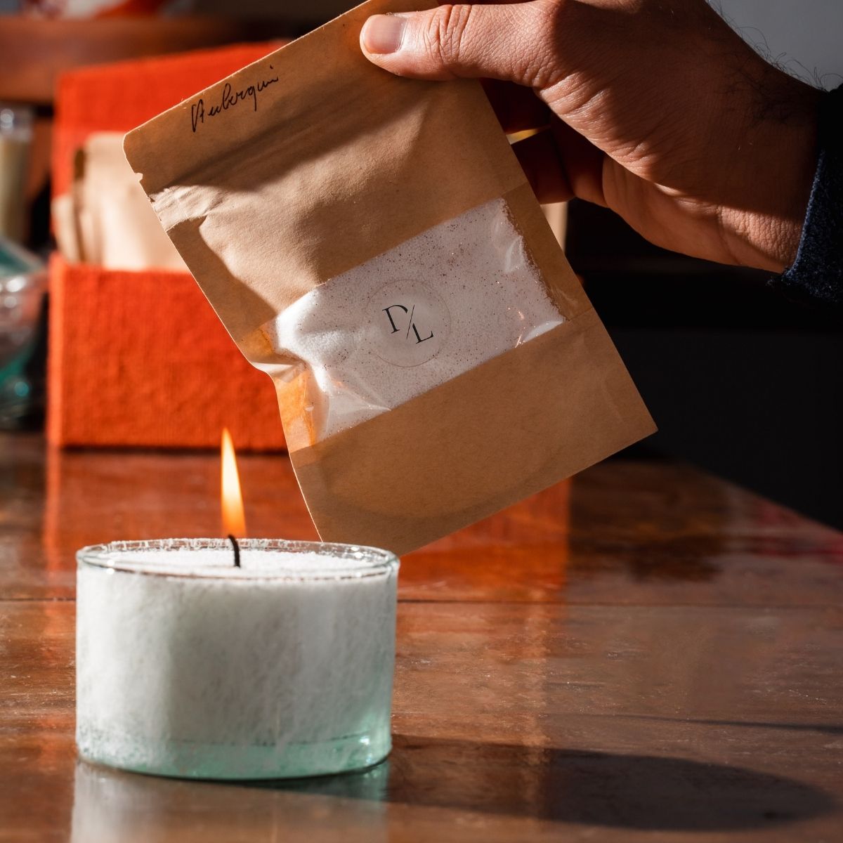 A delicate white textured glass vessel filled with white sand wax candle, softly lit to cast a serene glow. Paired with a Dary Living refill bag, this elegant combination embodies sustainable luxury and artisanal craftsmanship.
