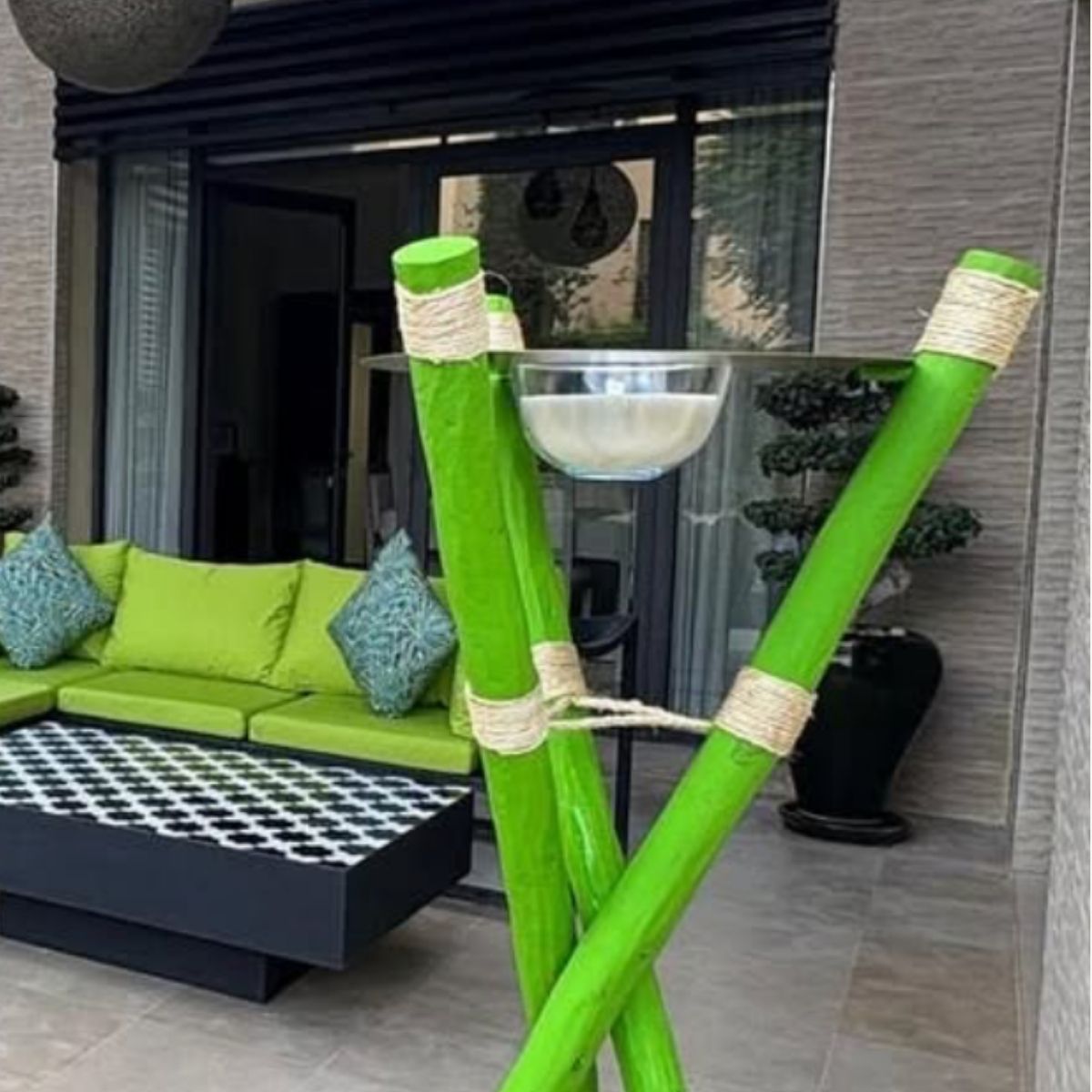 Green wooden stands with metal cylinder tops and glass bowls  in a modern outdoor setting